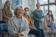 © Zireael - Elderly Woman Smiling in Doctors Waiting Room with Diverse Patients