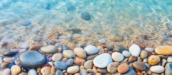 Wall Mural - Close-up of smooth beach pebbles under clear water on the sand, creating a natural and tranquil vacation-themed copy space image.