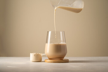 Protein powder. Pouring chocolate drink in a glass.