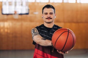 Wall Mural - Handsome tattooed hispanic male basketball player with a ball in his hands