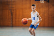© Zamrznuti tonovi - Junior basketball player dribbling a ball at court on training.