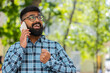 © Andrii Iemelianenko - Happy Indian bearded man having remote conversation communicate speaking by smartphone outdoors. Hispanic guy talking on phone unexpected good news gossip on city street. Town lifestyles. Horizontal