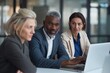 © mattegg - Three diverse professionals discuss business strategies while using a laptop