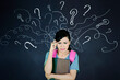 © Creativa Images - Confused Student Holding Books in Front of Blackboard With Question Marks