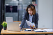 © David - Asian Businesswoman Using laptop computer and working at office with calculator document on desk, doing planning analyzing the financial report, business plan investment, finance analysis concept.