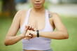 © DragonImages - Focused woman in sportswear checking her smartwatch during an outdoor exercise routine in a park