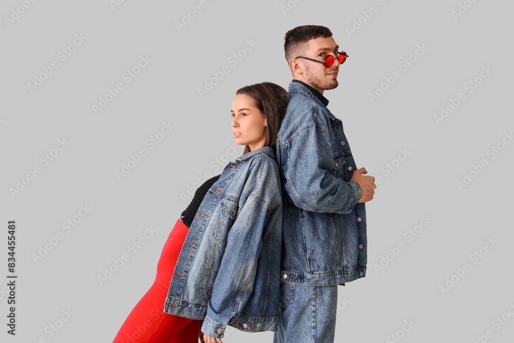 Stylish young couple in denim jackets on light background