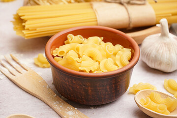 Wall Mural - Bowl with uncooked pasta on light background, closeup