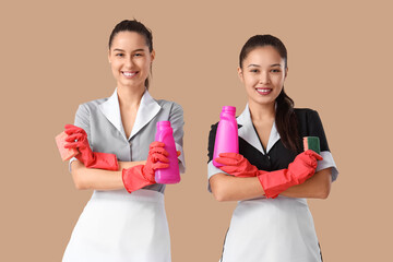 Canvas Print - Young chambermaids with cleaning sponges and detergents on brown background