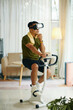 © DragonImages - A man using a VR headset while riding a stationary bike in a stylish, modern living room with plants and bright lighting