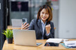 © David - Young busy smart serious Asian Japanese business woman executive holding cellphone device using mobile cell phone looking at smartphone working in corporate office with laptop computer technology.