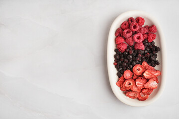 Sticker - Bowl with tasty freeze-dried raspberries, strawberries and blueberries on white background