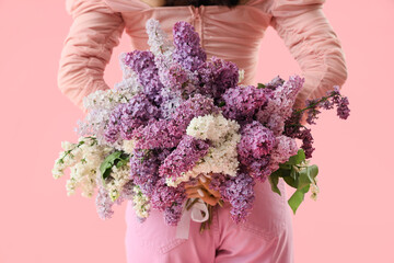 Poster - Beautiful young woman with lilac flowers on pink background, back view