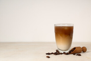 Wall Mural - Glass of iced latte and wooden scoop with coffee beans on white background