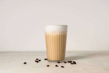 Wall Mural - Glass of iced latte and coffee beans on white background