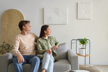 Young couple looking at paintings on light wall in room