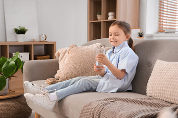 Poster - Cute little girl with glass of water sitting on sofa at home