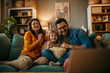 © La Famiglia - Family, mom dad and daughter holding a popcorn pot and laughing while watching a TV