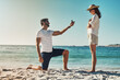 © peopleimages.com - Love, engagement and couple on a beach, proposal and relationship for commitment, vacation and support. Surprise, man and woman on seaside holiday, sunshine and ask for hand, marriage with ring