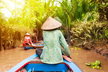 Wall Mural - Woman with asian hat rowing in a boat on jungle river