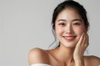 © Surachetsh - Portrait of beautiful young asian woman with clean fresh skin on white background, happy smile and hand touch face isolated over grey color backdrop. Beauty treatment concept.