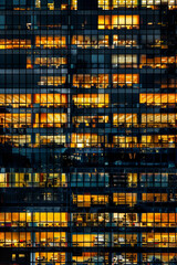 Wall Mural - An office building at night, filled with glowing windows like the lights of an urban cityscape, captures the symmetrical arrangement and grid effect. 