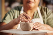 © Seventyfour - Close up detail shot of senior woman carefully shaping clay piece enjoying pottery class in sunlight copy space