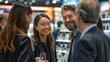 © Surachetsh - happy business people at the exhibition, smiling and talking to each other in front of a stand with lighting on it, having fun together in a candid shot,