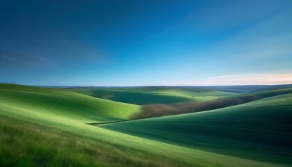 Wall Mural - 
Rolling hills of emerald green fields stretch to the horizon, framed by a clear blue sky.
