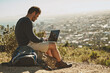 © C Pendl�/peopleimages.com - Exploration, man and hiker with laptop outdoor for remote work, connection and location review. Male person, freedom and computer in nature for typing, research and planning adventure blog or website