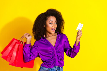 Wall Mural - Photo portrait of attractive young woman hold shopping bags credit card dressed stylish violet clothes isolated on yellow color background