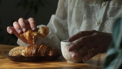 Wall Mural - Woman eating croissant and drinking coffee enjoying morning breakfast.