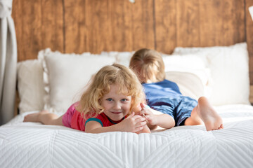 Poster - Cute sweet toddler children, tickling feet on the bed, laughing and smiling