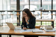 © Thitisak - Asian woman talking on smartphone with customer Business matters