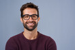 © Jordaan/peopleimages.com - Studio, glasses and man with portrait, proud and wellness with eye care, product and lens for vision. Blue background, face and happiness for person, prescription and eyewear with fashion in USA