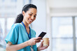 © Meeko Media - Smiling Female Doctor in Hospital Scrubs Using Smartphone with Coffee