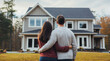 © OpticalDesign - Young couple hugging looking at their newly purchased home, real estate concept, suburban home, new house property, buying and investing in their dream home, purchase hd