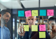 © peopleimages.com - Business, teamwork and brainstorming with sticky notes on glass for planning sales project, strategy process or tasks. Collaboration, mature CEO and employees in meeting for ideas, solution and goals