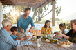 © peopleimages.com - Happy family, eating and lunch with food on patio outdoor with conversation, bonding or healthy meal in summer. Parents, grandparents and kids at dining table in backyard of home with love or talking
