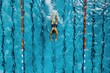 © Fotograf - A person swimming laps in a clear blue pool with sunlight reflecting off the water