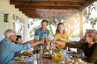 © peopleimages.com - Cheers, wine and family in backyard for food, celebration and eating in happy bonding together at table. Children, parents and grandparents toast with drinks, smile and lunch on patio for holiday fun