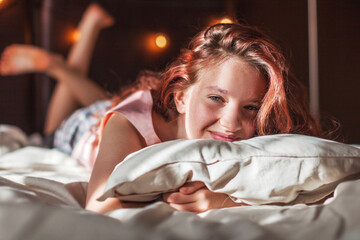 Wall Mural - Happy young girl lying in bed in the morning