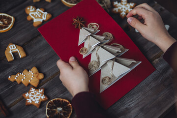 Wall Mural - Little boy holding handmade card made with recyclable natural materials, zero waste, sustainable lifestyle, hobby. Concept of christmas leisure, family time, do it yourself present.