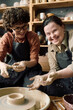 © AnnaStills - Vertical shot of cheerful woman with Down syndrome and her female friend enjoying pottery class together in modern workshop