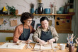 © AnnaStills - Mature female artisan sitting next to her student with Down syndrome teaching her how to roll out clay