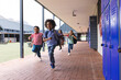 © WavebreakMediaMicro - In school, diverse group of young students running in hallway outdoors, copy space