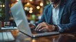 © admin_design - A businessman works on his laptop at a cafe table, focusing on his work.