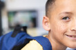 © Wavebreak Media - Biracial boy in yellow smiles excitedly in classroom, ready for school.