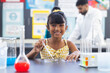 © Wavebreak Media - Biracial girl in yellow conducts experiment, male scientist watches