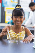 © Wavebreak Media - Biracial girl in a yellow dress conducts a science experiment in school